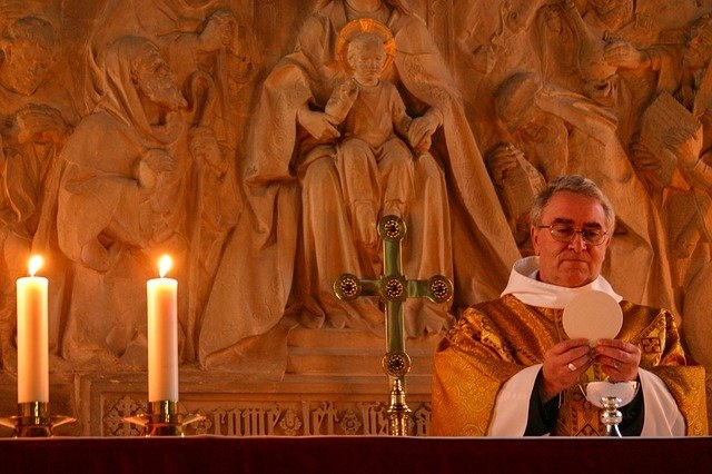 A priest holding a Host over a chalice